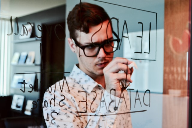 man writing on transparent board about leads